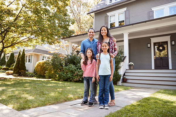 a happy family smiling in front of their home, which features new construction.